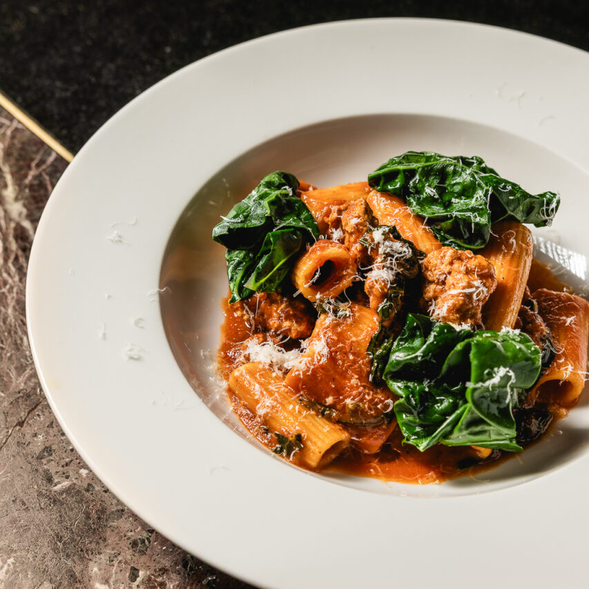 Aerial view of Melbourne's cityscape featuring the Yarra River, modern skyscrapers, historic buildings, lush greenery, and a clear blue sky.