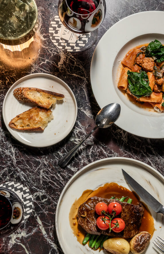 Spread of dishes at Woods Restaurant as part of View Hotels including red wine and steak