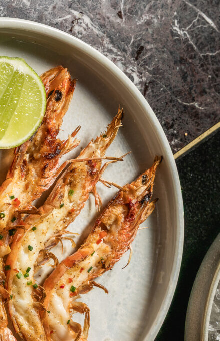 A modern hotel room with a king-sized bed, contemporary artwork, wooden furniture, and large windows with views of a cityscape.