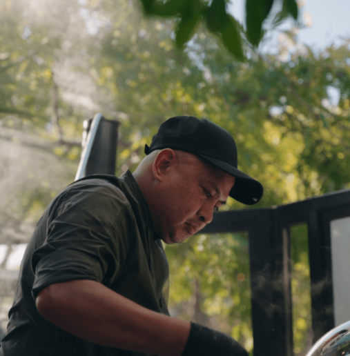 A modern hotel room featuring two neatly made beds, a floor-length window with city view, bedside tables with lamps, and a wall-mounted TV. Bright, inviting atmosphere.