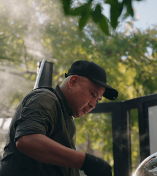 A modern hotel room featuring two neatly made beds, a floor-length window with city view, bedside tables with lamps, and a wall-mounted TV. Bright, inviting atmosphere.