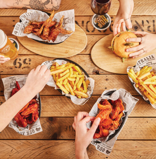 A lush garden with vibrant flowers, manicured hedges, and a serene walkway. Tall trees provide shade, creating a peaceful and inviting outdoor space for visitors.