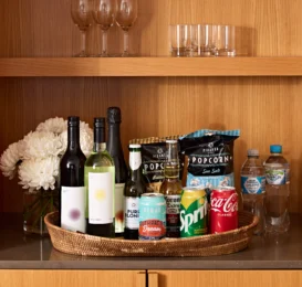Elegant minibar with wines, snacks, fresh flowers, and glassware for a relaxing hotel stay.