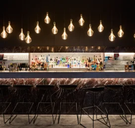 Chic hotel bar with modern lighting and a stocked drinks display, inviting seating, perfect for evening relaxation.