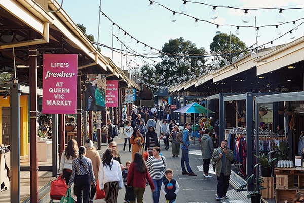 A bustling day at Victoria Queen Market with crowds of people browsing through stalls, enjoying the lively atmosphere, Melbourne, Australia
