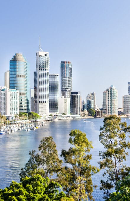 Brisbane Cityscape with a river and a lot of tall buildings under the blue sky with blue water river surrounded by trees in a sunny day in Queensland, Australia.