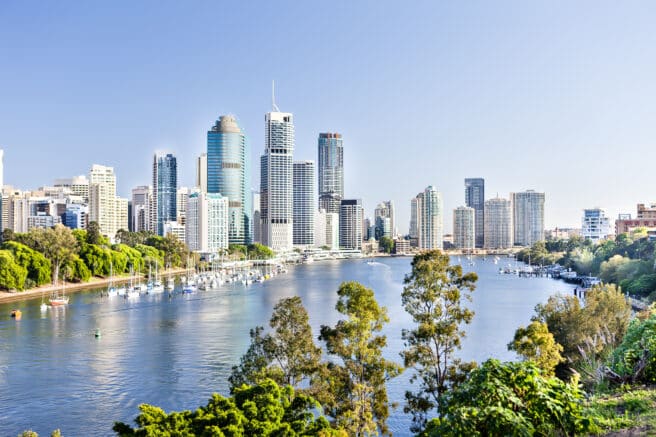 Brisbane Cityscape with a river and a lot of tall buildings under the blue sky with blue water river surrounded by trees in a sunny day in Queensland, Australia.