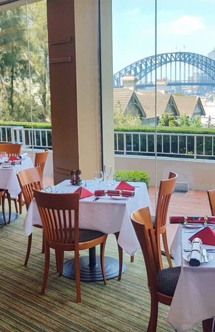 Image of LB's Restaurant Decorated with Christmas napkins and bon bons, with a view of the Harbour Bridge in the background.