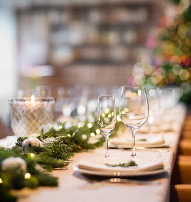 Christmas dinner feast. A decorated dining table with champagne glasses and christmas tree in background.