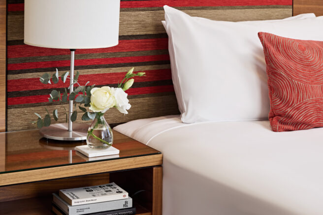 Image of a hotel room with a large bed, two chairs, a round table, and a window with curtains. The decor is modern and the atmosphere inviting.