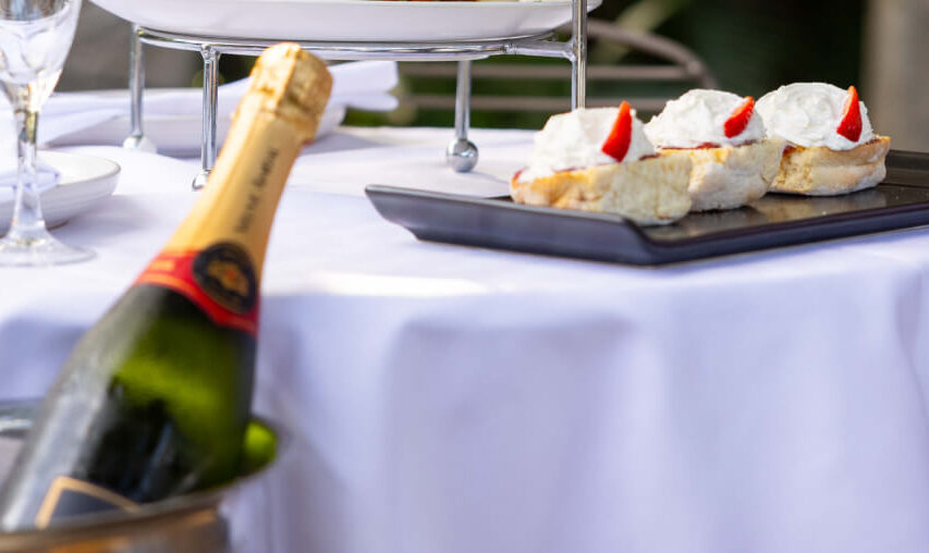 A happy family of four, with two children, enjoys a celebratory meal outdoors. They are seated at a table adorned with flowers and a variety of delicious-looking food.
