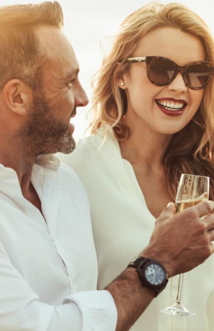 Man and woman in the sun cheersing sparkling wine.