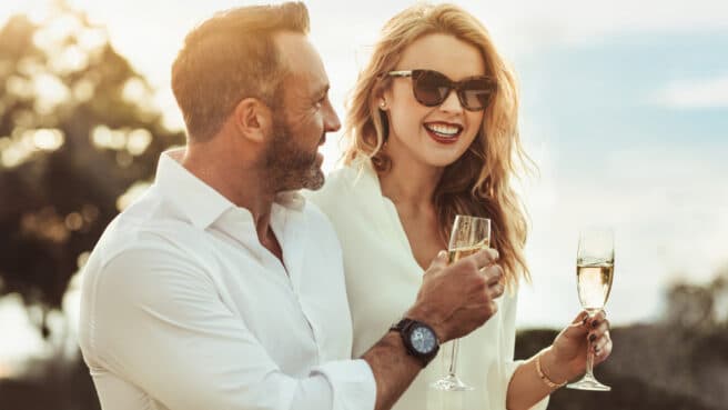 Man and woman in the sun cheersing sparkling wine.