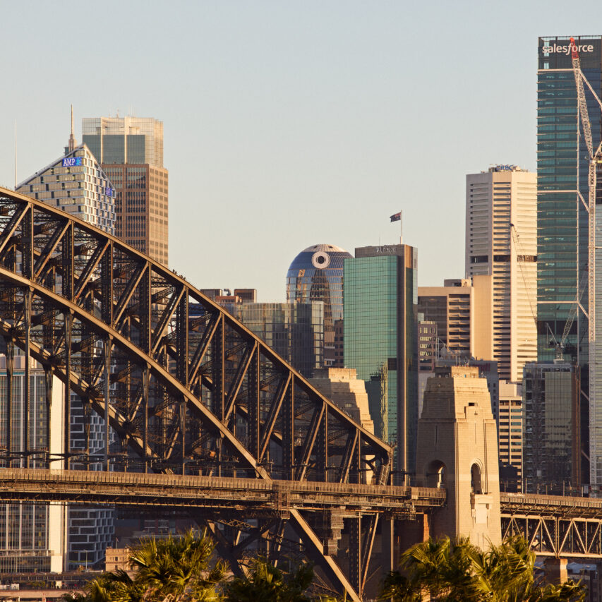 Aerial view of View Hotel, surrounded by lush greenery and adjacent to a river, with a clear blue sky above.