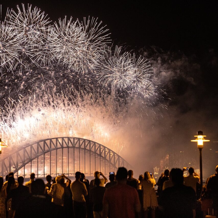 Guests enjoy vibrant fireworks over iconic bridge at night, creating a festive atmosphere near hotel with city views.