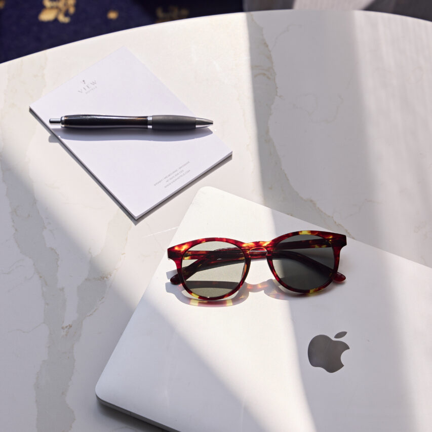 A spacious hotel room with a large bed, modern decor, a seating area, and large windows offering a view of the cityscape.