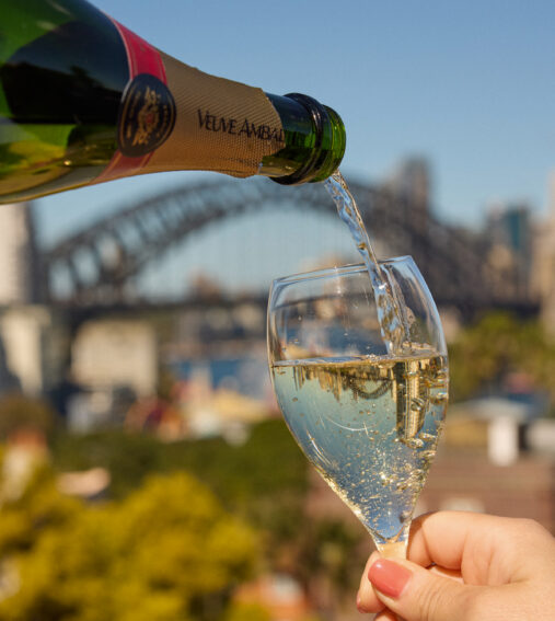 Aerial view of Sydney Harbour featuring the iconic Opera House and Harbour Bridge under a clear blue sky, surrounded by cityscapes and water.