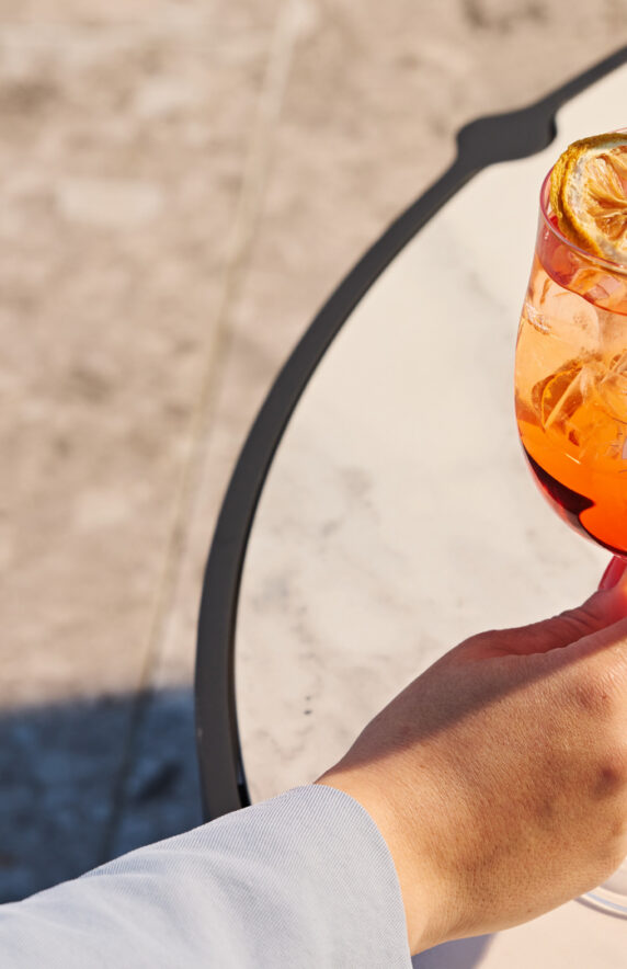 The image shows a modern, well-lit hotel room featuring a king-size bed, decorative wall art, a chair, and a side table with a lamp, offering a cozy atmosphere.