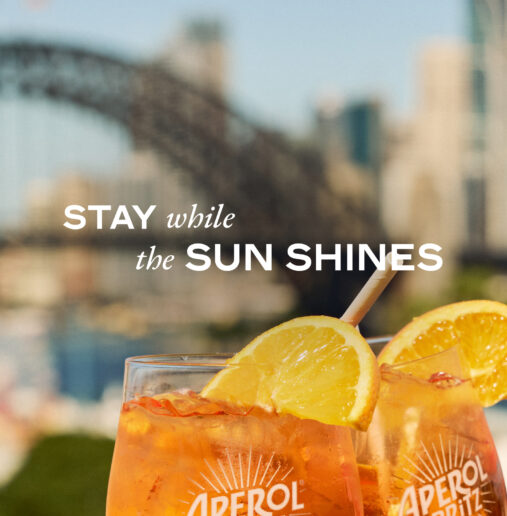 A diverse group of smiling individuals, standing closely for a group photo, in a well-lit interior space with neutral-colored walls and a simple, modern décor.