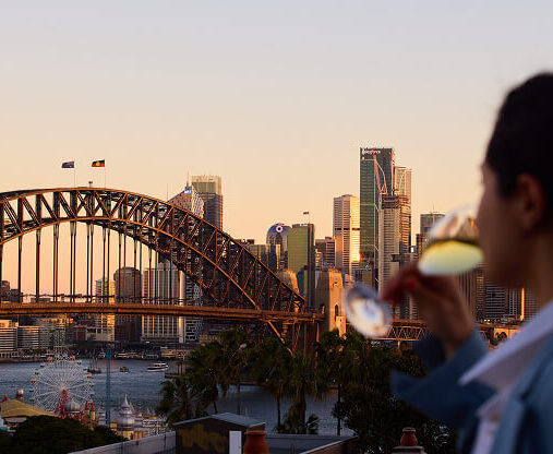 A modern hotel building at night, beautifully illuminated with lights. The structure is surrounded by cityscape and trees, giving it an inviting and contemporary ambiance.