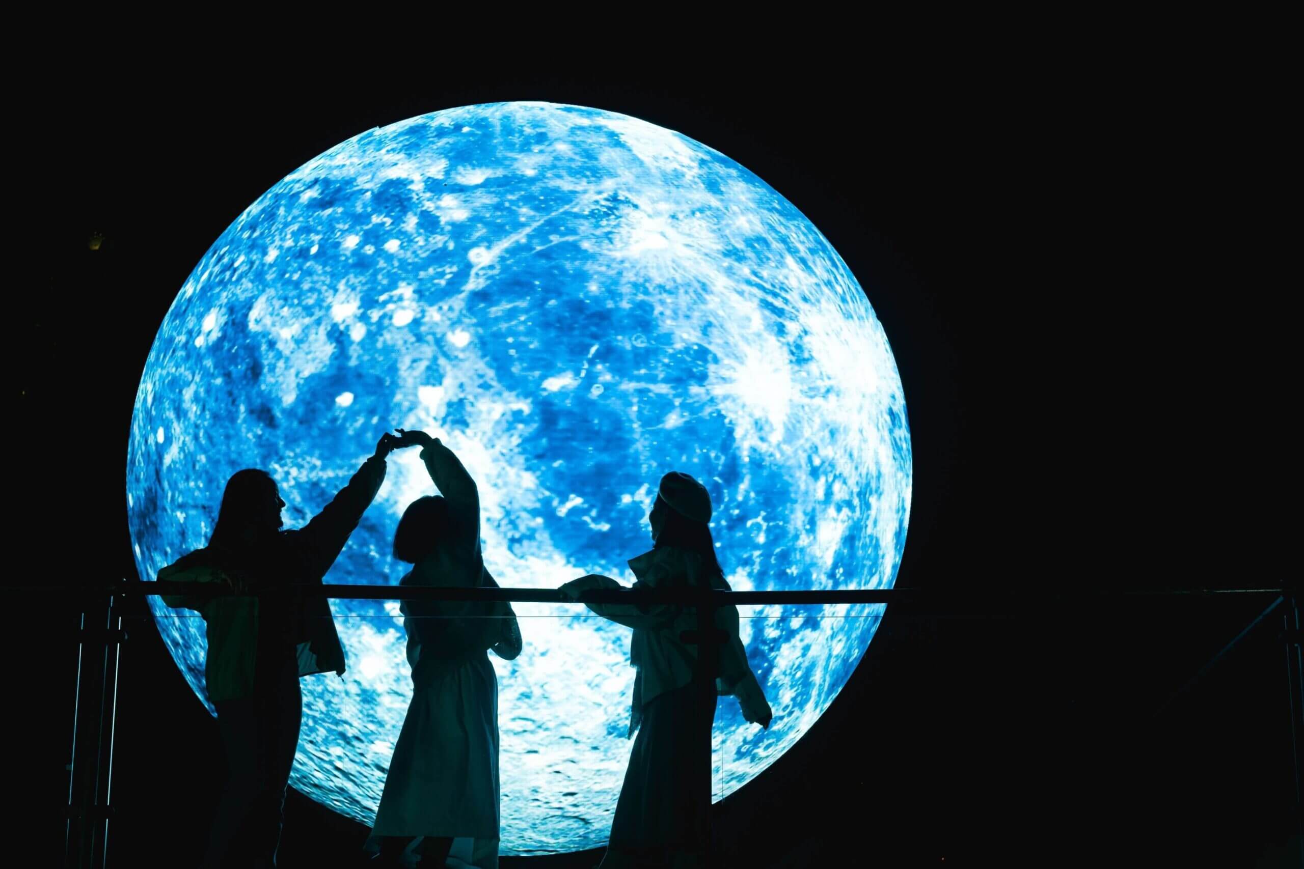 Friends enjoying the Fly To The Moon installation at Barangaroo during Vivid 2025. The moon has long been a source of light and inspiration, offering a nightly glimpse into the vast mysteries of space. Fly to the Moon invites you to bask in its luminous glow and step into a moment of pure whimsy and play.