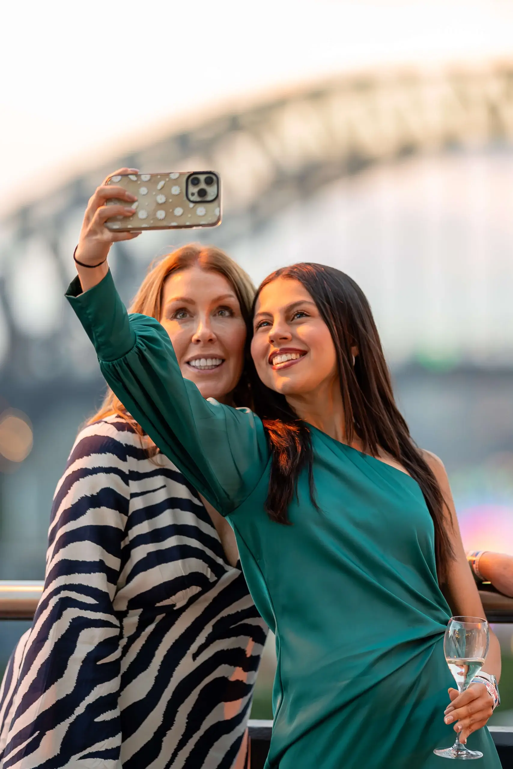 Two guests taking a photo on the terrace at golden hour with the Harbour Bridge behind