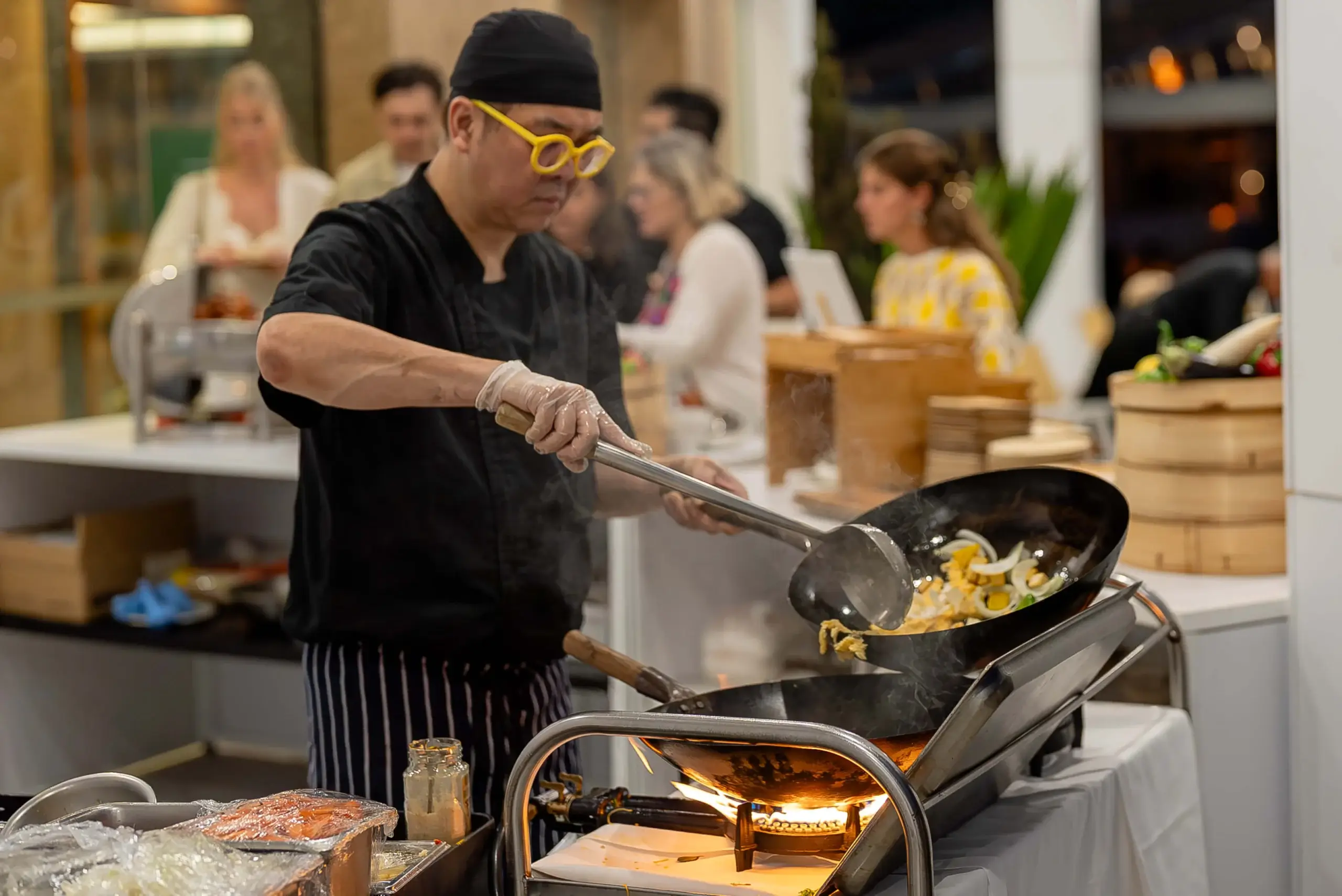 A chef cooking to order over a wok at a live food station