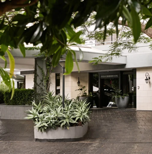 View Brisbane porte-cochère with shaded driveway, potted greenery, mature trees and elegant entrance canopy for easy drop-off and luggage access