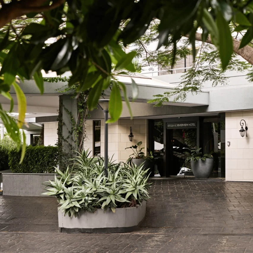 View Brisbane porte-cochère with shaded driveway, potted greenery, mature trees and elegant entrance canopy for easy drop-off and luggage access